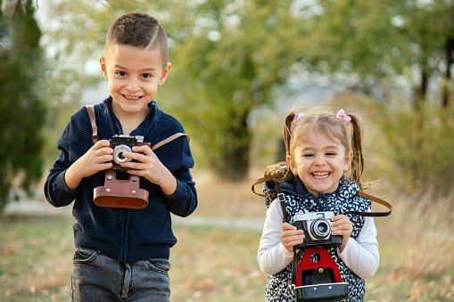 Little boy and a girl learning how to use a photo camera