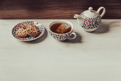 Tea time with homemade whole wheat biscuits on white wooden background