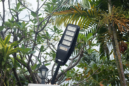 Small street solar light on wall around building below tree in residential district of Bangkok Ladprao