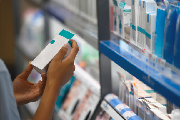 Close-up of young woman buying nose drops in drugstore