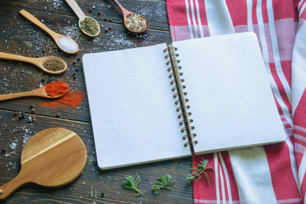 istock Recipe book on dark kitchen table. Wooden spoons with spicy. Copy space 1440796677