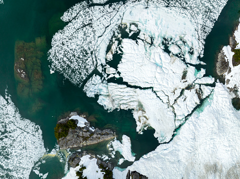Shoreline of a frozen alpine lake. Aerial view of a nature background.