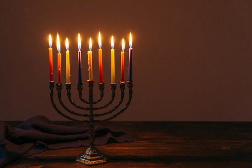 Jewish Holiday Hanukkah background with candles and traditional candelabra menorah on dark background. Jew festival of lights concept