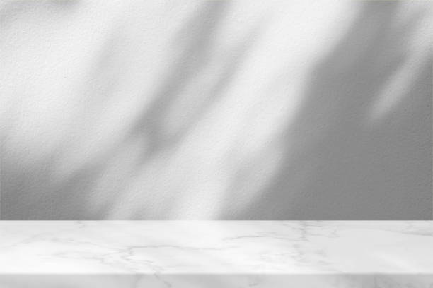 istock Marble Table with White Concrete Wall Texture Background with Light Bokeh Beam and Shadow, Suitable for Product Presentation Backdrop, Display, and Mock up. 1440805367