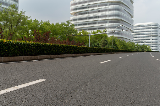 empty asphalt road in front of modern office buildings exterior.