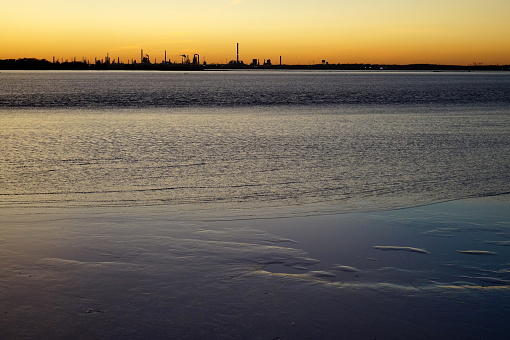 Industrial skyline at sunset, view across Delaware River, from Fort Mott on New Jersey side, Pennsville Township, NJ, USA