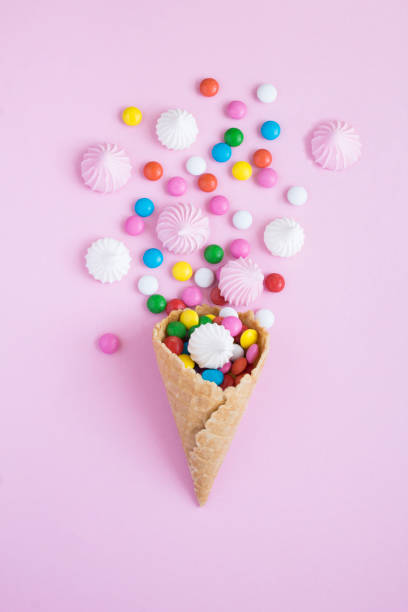 istock Ice cream cone with meringue and candy on the pink background. Top view. 1440808216