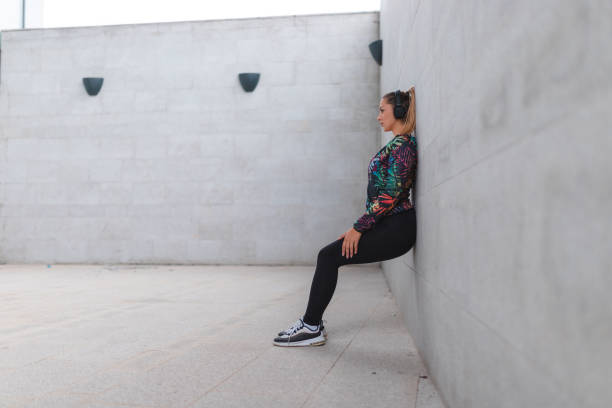 istock Young athletic woman doing the wall sit exercise outdoors 1440808375