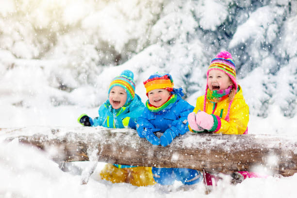Kids playing in snow. Children play outdoors in winter snowfall.