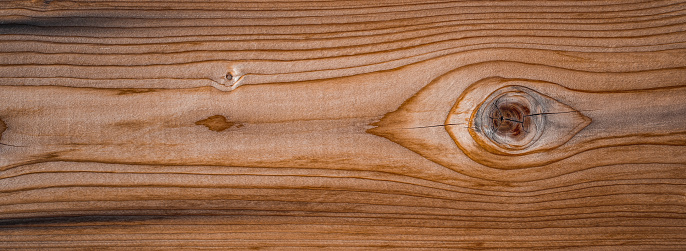 Weathered and scratched rustic wooden board.High angle view of a flat textured wooden board backgrounds. It has a beautiful nature and abstractive pattern. A close-up studio shooting shows details and lots of wood grain on the wood table. The piece of wood at the surface of the table also appears rich wooden material on it. The wood is dark brown color with darker brown lines and pattern on the bottom. Flat lay style. Its high-resolution textured quality.The close-up gives a direct view on the table, showing cracks and knotholes in the wood.