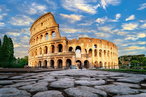 The Colosseum at sunset in Rome, Italy. Low angle view of the main facade of the Colosseum and, in the foreground, the ancient paving in polished stone slabs.