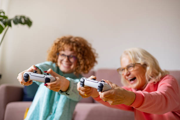 grand-mère et petite-fille en compétition et en train d’encourager tout en jouant à la playstation - child little girls television playstation photos et images de collection