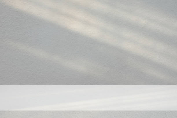 istock Stucco Table with White Concrete Wall Texture Background with Light Beam and Shadow, Suitable for Product Presentation Backdrop, Display, and Mock up. 1440810978