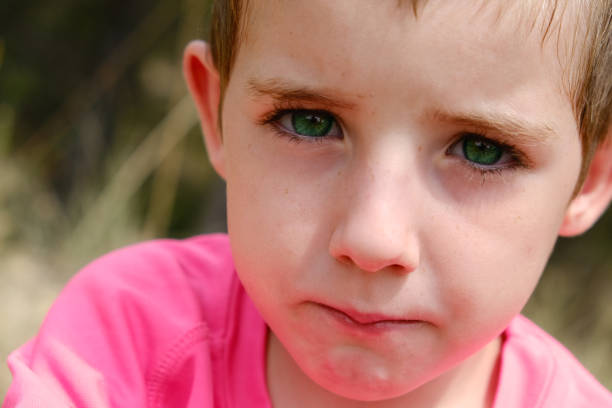 Little girl with blue eyes. Girl with pink hair in a cap outdoors.