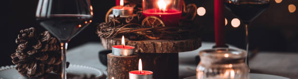 istock Rustic table decor for Christmas or New Year family dinner. Centrepiece with red candle, dry orange, cone, cinnamon, anise. Zero waste eco-friendly home. Cozy atmosphere, dark background. Banner 1440814776