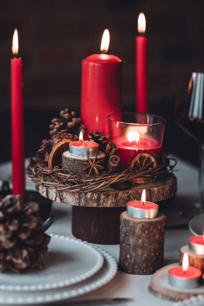 istock Rustic table decor for Christmas or New Year family dinner. Centrepiece with red candle, dry orange, cone, cinnamon, anise. Zero waste eco-friendly home. Cozy atmosphere, dark background. Close up 1440814844