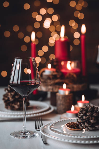 rustic table decor for christmas or new year family dinner. centrepiece with red candle, dry orange, cone, cinnamon, anise. zero waste eco-friendly home. cozy atmosphere, dark background. close up - wine christmas stockfoto's en -beelden