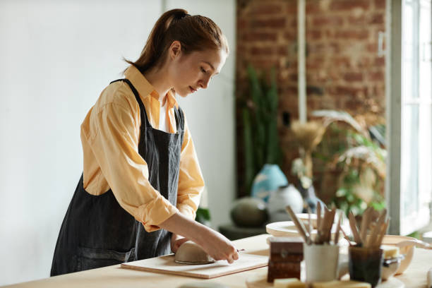 istock Young woman creating handmade ceramic bowl in cozy pottery studio 1440817547