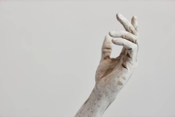 Minimal closeup of male hand covered in white paint Minimal closeup of male hand covered in white paint or plaster, human art form, copy space clay sculpture stock pictures, royalty-free photos & images
