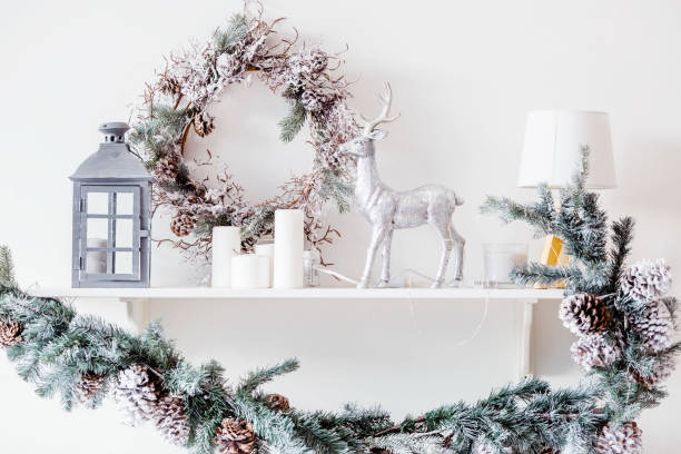 istock Christmas decoration on a shelf in a white interior with Christmas garlands. Flashlight, deer, candles and a Christmas tree. Scandinavian style. Postcard for the new year. 1440818421