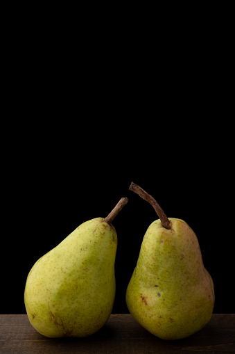 Bartlett pears on a wood surface with a black background