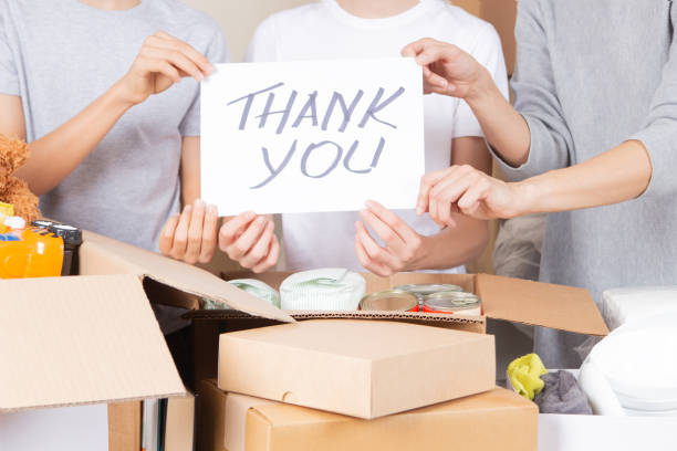 thank you for donation. volunteers collecting donations for charity. teenagers and woman hands holding paper sheet with message thank you over cardboard boxes full of food grocery, clothes, toys - charity and relief work donation box thank you child imagens e fotografias de stock