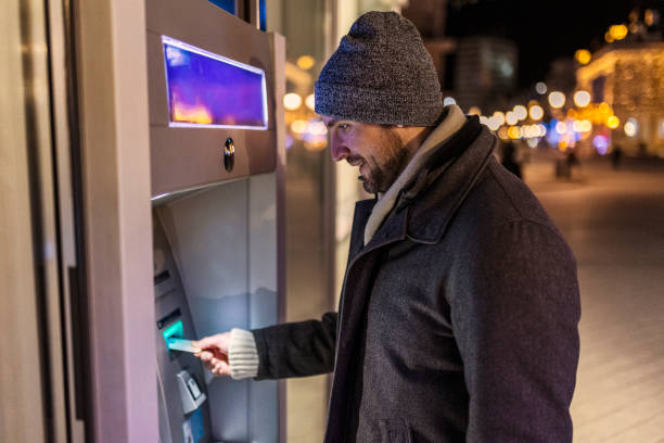istock Young man inserting credit cart to atm 1440824199