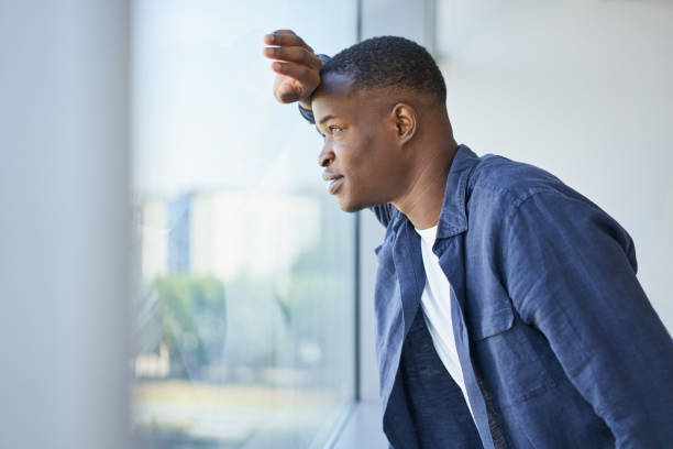 istock Young African American man looking out the window in an office 1440829757