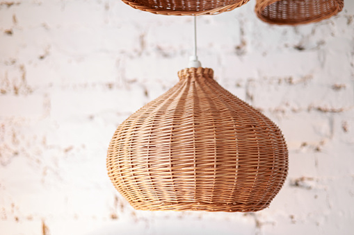 three rattan chandeliers different forms on white brick wall background. Straw lampshade in cozy living room. Eco-friendly interior design using natural materials. Scandinavian interior. copy space.