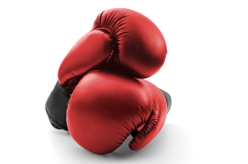 Competitive sports, fist protection and martial arts concept with photograph of two red boxing gloves with one glove on top of the other isolated on white background with clipping path cutout