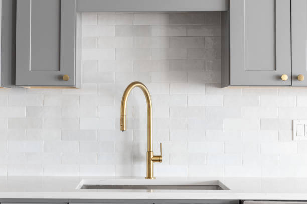 istock A gold faucet in a grey and white kitchen. 1440834373