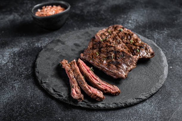 Traditional barbecue skirt steak sliced on a cutting board.  Black background. Top view Traditional barbecue skirt steak sliced on a cutting board.  Black background. Top view. marbled meat stock pictures, royalty-free photos & images