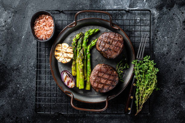 istock Grilled Fillet Mignon Steak with roasted asparagus. Black background. Top view 1440837998