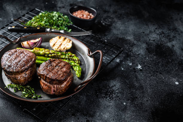 istock Grilled Fillet Mignon Steak with roasted asparagus. Black background. Top view. Copy space 1440838021
