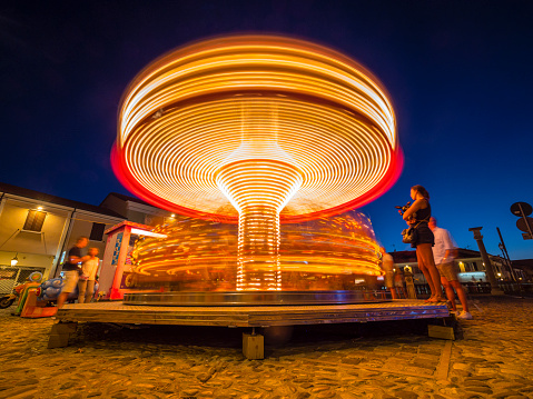 Cesenatico, Italy - August 04, 2022: A colorful carousel spinning at night on Piazza Carlo Pisacane near Porto Canale Leonardesco.