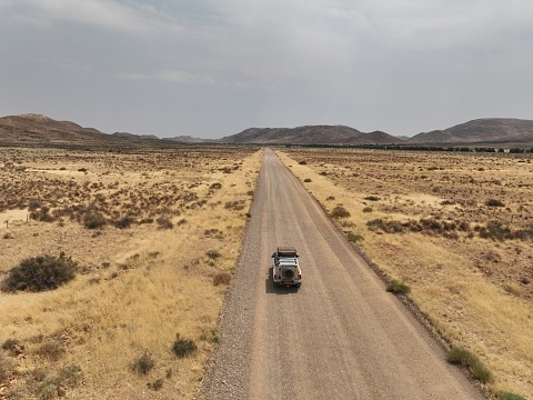 Car drives over gravel road in Namibia photographed with a drone