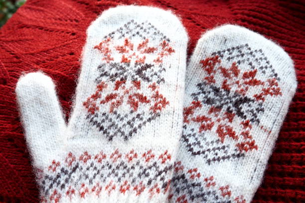 istock Fluffy white knitted mohair mittens with a traditional floral pattern on the back. A pair of mittens fashion accessories. Knitted with red and black threads geometric jacquard pattern. Winter clothes. 1440842760