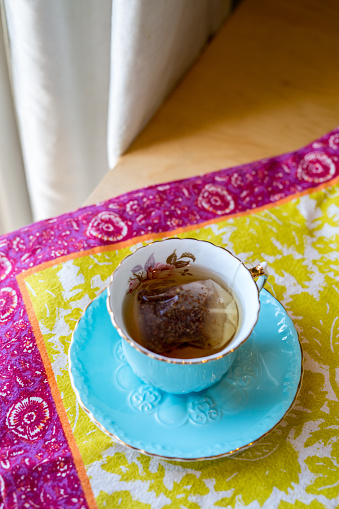 Hot herbal tea in a beautiful ornate blue teacup on a colourful placemat