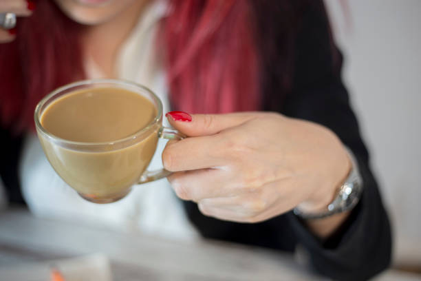 Young girl hands with Ombre manicure holding cup of coffee or tea on white desk. Beauty and manicure concept image. Close up, selective focus
