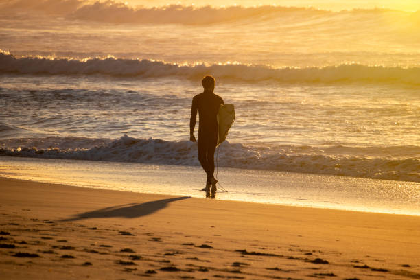 istock Surfer walking observing the surf on a beach at sunrise 1440848016