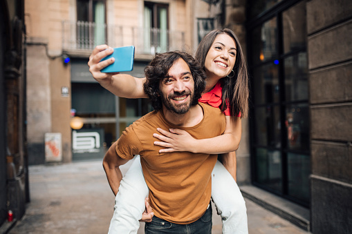 Portrait of a young couple in Barcelona enjoying their journey and taking a selfie.