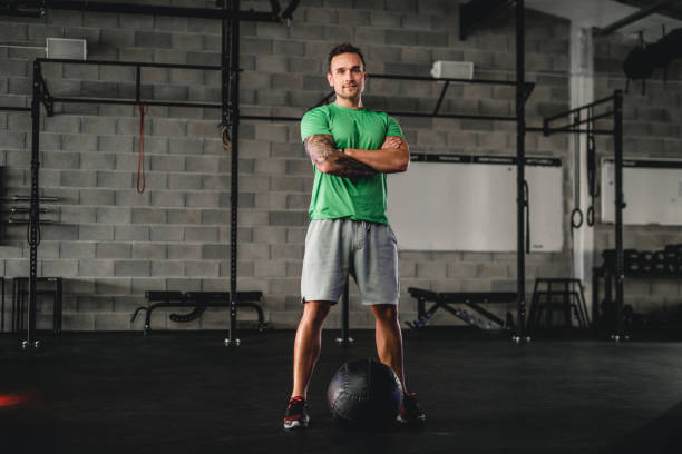 gymnase portrait d’un jeune homme confiant avec ballon médicinal - short de course à pied photos et images de collection