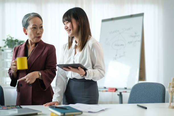 istock Mature female manager  discussing work, training young interns at corporate office. 1440868007