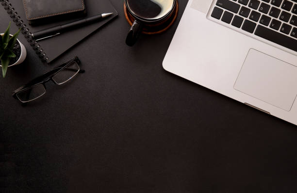 istock Top view laptop, glasses, notebook and coffee cup on black office desk. 1440868478