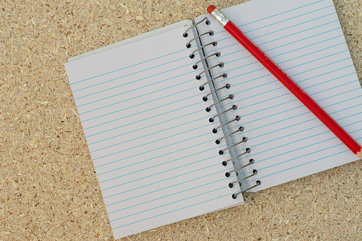 Blank open notebook on a table with red pencil and copy space