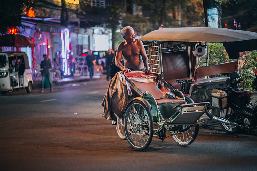 Cambodia, Phnom Penh, November 11, 2022, The traffic with a bicycle ricksha taxi on the road ,in the city of Phnom Penh, Cambodia.