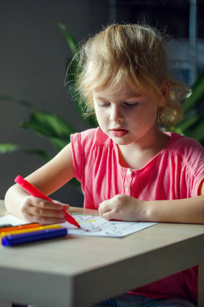istock Child drawing a picture with colored markers, sitting at the table 1440879442