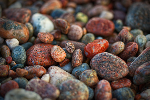 Horizontal image of smooth wet red, white, pink, gray and brown pebbles lying on a Lake Superior Beach, Agawa Bay, Ontario.