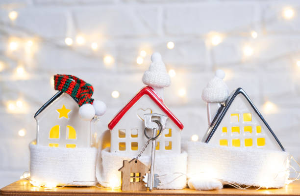 Key to the house with a keychain on a cozy home with a Christmas decor. A gift for New Year, Christmas. Building, design, project, moving to new house, mortgage, rent and purchase real estate stock photo