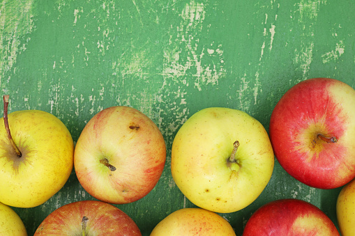 red and yellow apples on the green wooden background